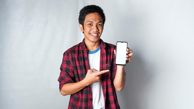 Foto homem asiático adulto vestindo camiseta de flanela vermelha segurando o telefone com cara de sorriso animado fundo branco isolado