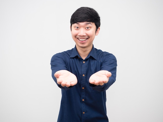 Homem asiático alegre com sorriso no rosto mostra mão vazia retrato fundo branco