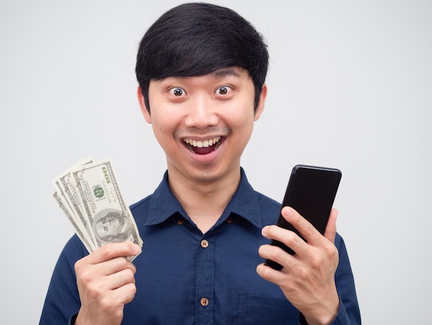 Homem asiático alegre rosto feliz segurando telefone celular e dinheiro dólar na mão retrato