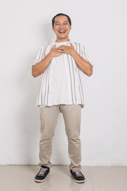 Homem asiático alegre sorrindo enquanto segura seu peito isolado no fundo branco