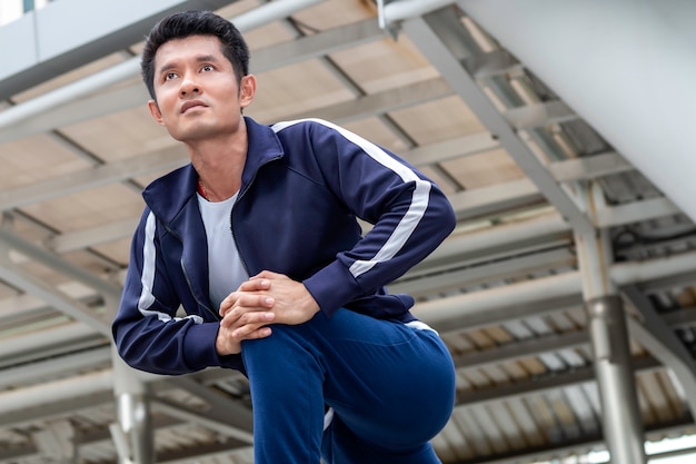 Homem asiático atleta em pose de início de corrida na rua da cidade.