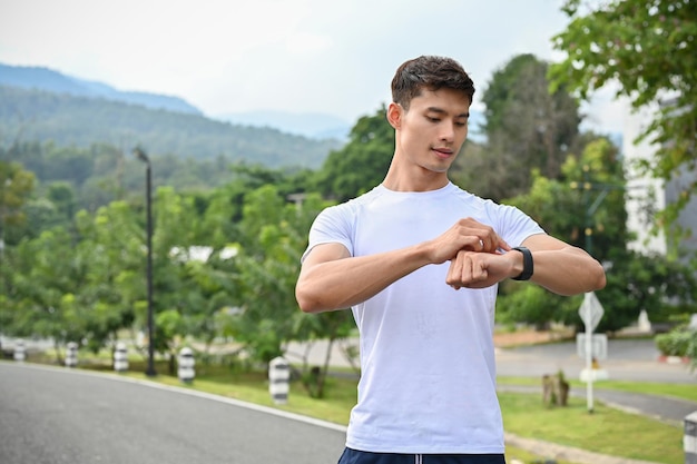 Homem asiático atlético verificando suas calorias queimando em seu smartwatch depois de uma longa corrida