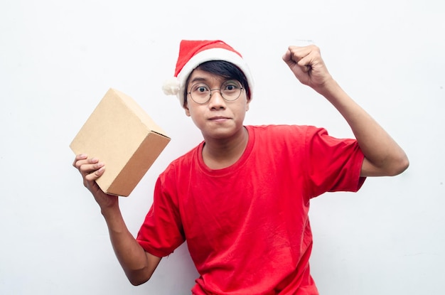 homem asiático atraente em roupas de tema de Natal vermelho segurando a caixa de papel de presente.