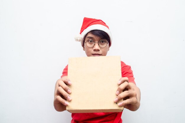 homem asiático atraente em roupas de tema de Natal vermelho segurando a caixa de papel de presente.