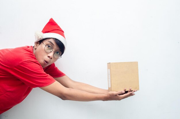 homem asiático atraente em roupas de tema de Natal vermelho segurando a caixa de papel de presente.