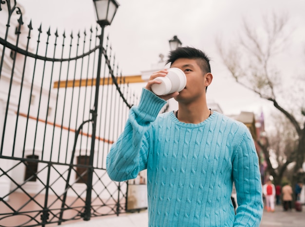 Homem asiático bebendo uma xícara de café.