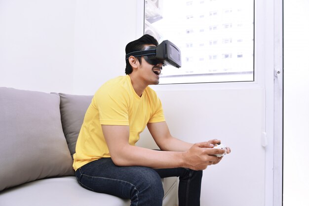 Homem asiático bonito usando realidade virtual enquanto estiver jogando videogame