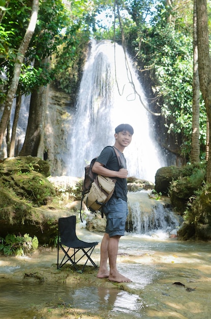 Homem asiático caminhando na frente da cachoeira