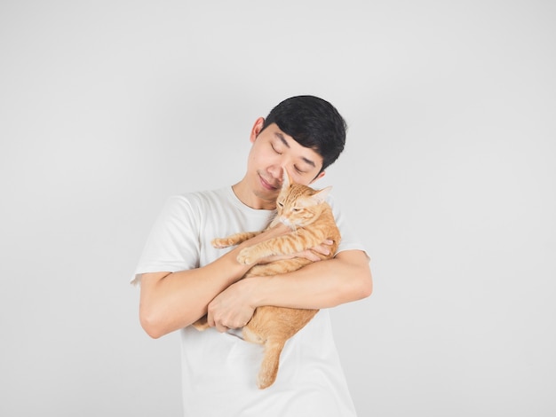 Homem asiático carregando e abraçando a adorável gata cor de laranja em fundo branco isolado