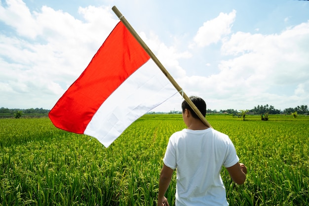 Homem asiático com bandeira da indonésia no topo da montanha