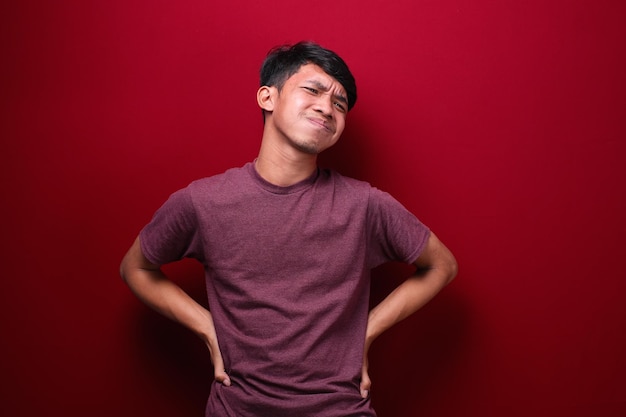 Homem asiático com dor de estômago no conceito de saúde de fundo vermelho