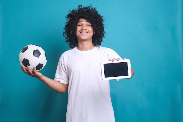 Homem asiático com peruca de cabelo encaracolado apoiando o time de futebol enquanto segura o celular para assistir soc