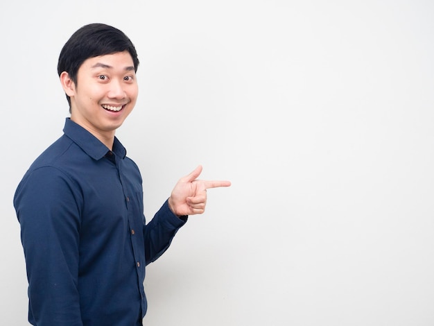 Homem asiático com sorriso feliz apontando o dedo para o espaço da cópia