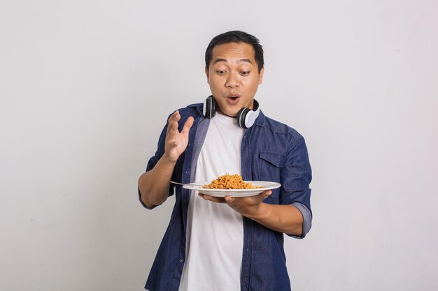 Homem asiático comendo macarrão instantâneo e fica surpreso com a sua delicadeza