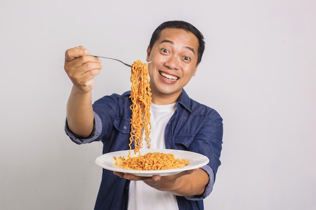 Homem asiático comendo macarrão instantâneo e fica surpreso com a sua delicadeza