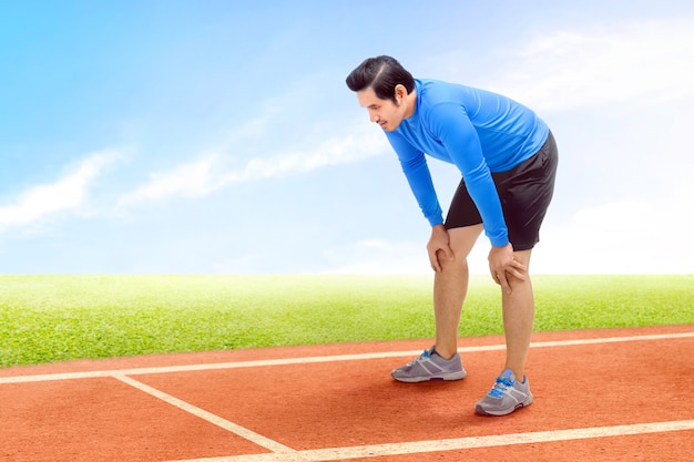 Homem asiático corredor fazer uma pausa depois de correr na pista de corrida