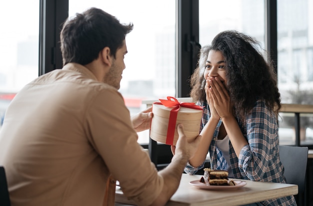 Homem asiático dando presente de aniversário para linda mulher emocional