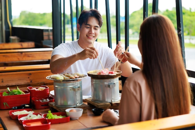 Homem asiático de felicidade almoçando com sua namorada no aniversário de namoro no restaurante grelhado