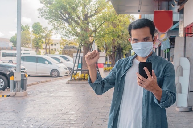 Homem asiático, desgastar, máscara facial, segurando, telefone celular, estilo vida, novo, normal, social, distanciamento