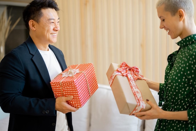 Homem asiático e mulher jovem dando presentes