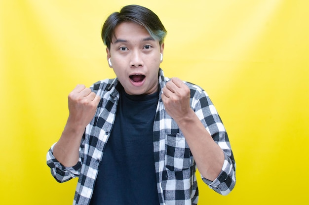 homem asiático em êxtase com cabelo peekaboo está feliz curtindo música com AirPods enquanto dança vibrando