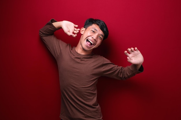 Homem asiático em fundo vermelho vestindo camiseta marrom com dor nas costas