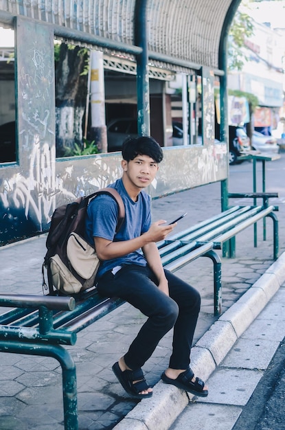 Homem asiático esperando no ponto de ônibus cheio de rabiscos