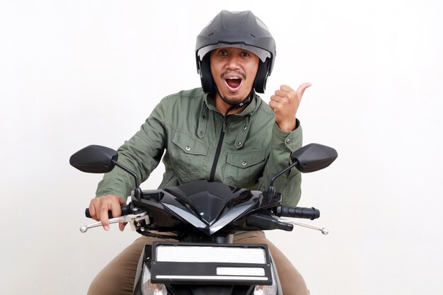 Foto homem asiático excitado apresentando de lado enquanto dirige motocicleta isolado em fundo branco