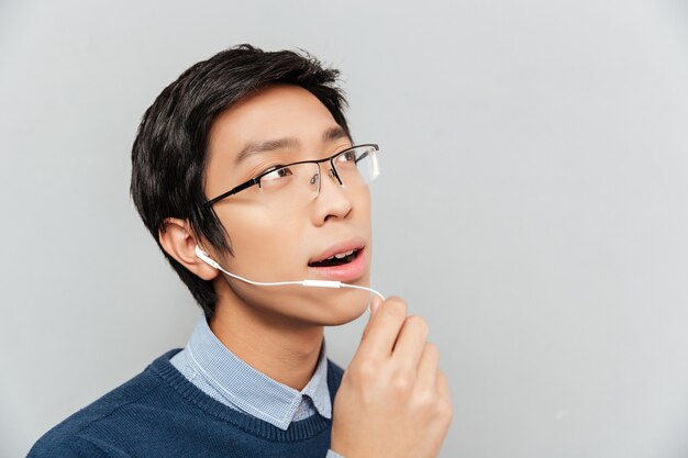 Homem asiático falando em fones de ouvido.