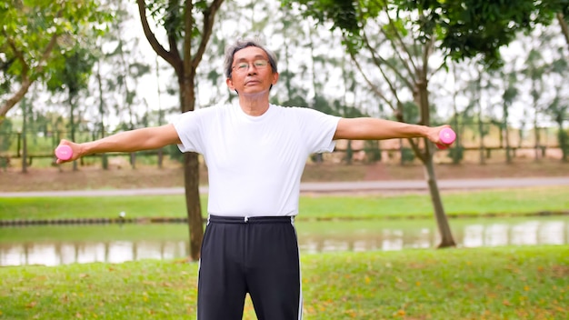 Homem asiático fazendo exercício, levantando halteres no parque.