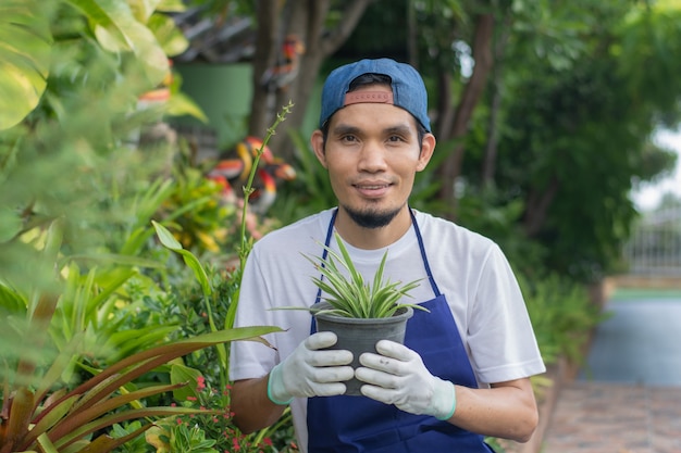 Homem asiático feliz de avental em um pequeno centro floral, proprietário de loja de plantas ornamentais Man