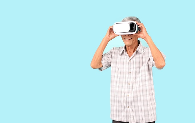 Foto homem asiático idoso jogando videogame vr com óculos de realidade virtual fundo azul em estúdio