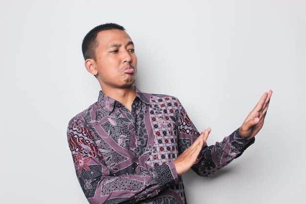 Homem asiático indonésio preocupado mostrando sinal de recusa dizendo não aumentar a atenção em pé