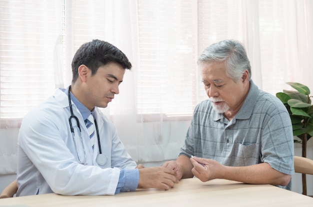 Homem asiático mais velho sênior perguntando jovem médico caucasiano sobre indicações e contra-indicações da nova medicina, cuidados de saúde e medicina conceito com espaço de cópia.