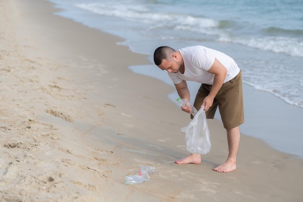 Homem asiático mantém lixo no interior do mar, voluntários da praia, mantendo garrafa de plástico de lixo