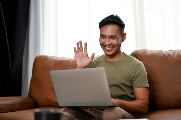 Homem asiático milenar inteligente tendo uma reunião online com sua equipe enquanto trabalhava em casa