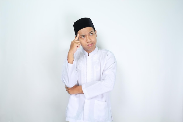 Foto homem asiático muçulmano pensativo tocando sua cabeça com o dedo isolado em fundo branco