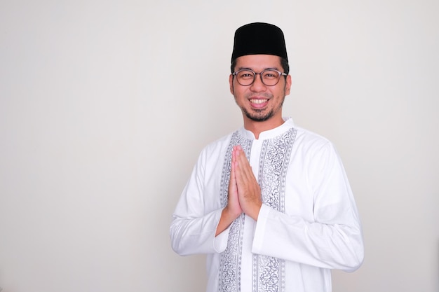 Foto homem asiático muçulmano sorrindo amigável ao fazer pose de saudação