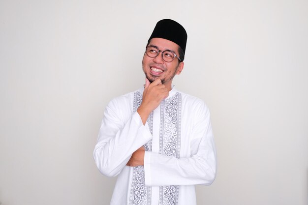Homem asiático muçulmano sorrindo feliz ao pensar em algo