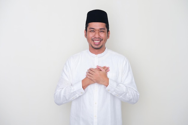 Homem asiático muçulmano sorrindo feliz com as duas mãos no peito