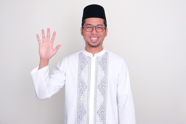 Homem asiático muçulmano sorrindo para a câmera enquanto mostra o sinal de cinco dedos