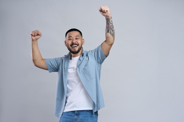 Homem asiático muito feliz levantando os punhos gritando gritando comemorando sua vitória