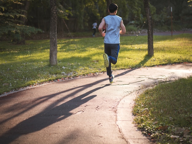 Homem asiático novo que corre no parque, conceito saudável do estilo de vida.