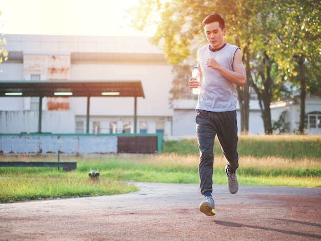 Foto homem asiático novo que corre no parque, conceito saudável do estilo de vida.