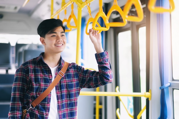 Homem asiático novo que guarda o punho do ônibus público.