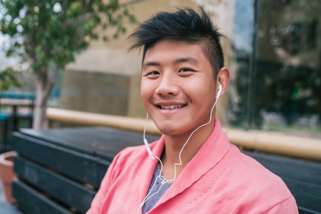 Homem asiático ouvindo música com fones de ouvido.