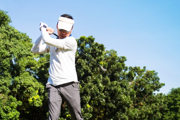 Homem asiático que bate o golfe no clube de golfe. Desporto ao ar-livre.