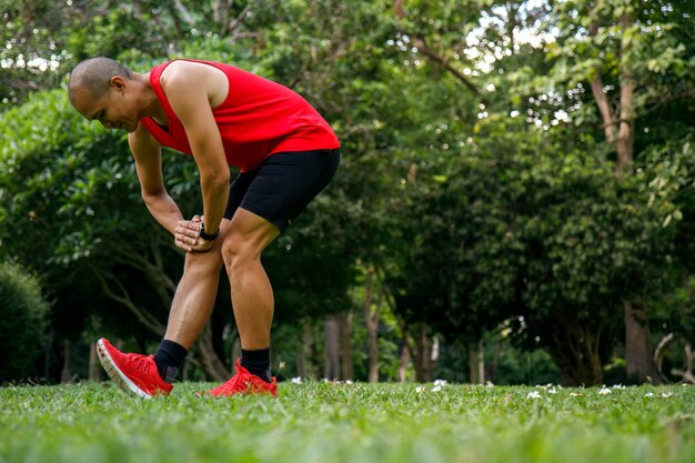 Homem asiático que estica no parque antes de correr na manhã.