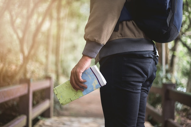 Foto homem asiático, segurando o mapa com mochila e andando na floresta