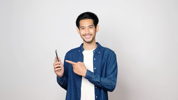 Homem asiático segurando um telefone celular isolado em um fundo cinza